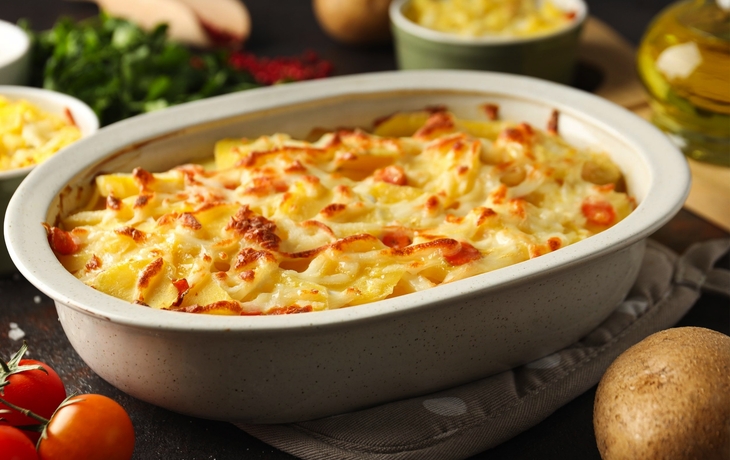 Kartoffelgratin in einer weißen Auflaufform auf einem Tisch.