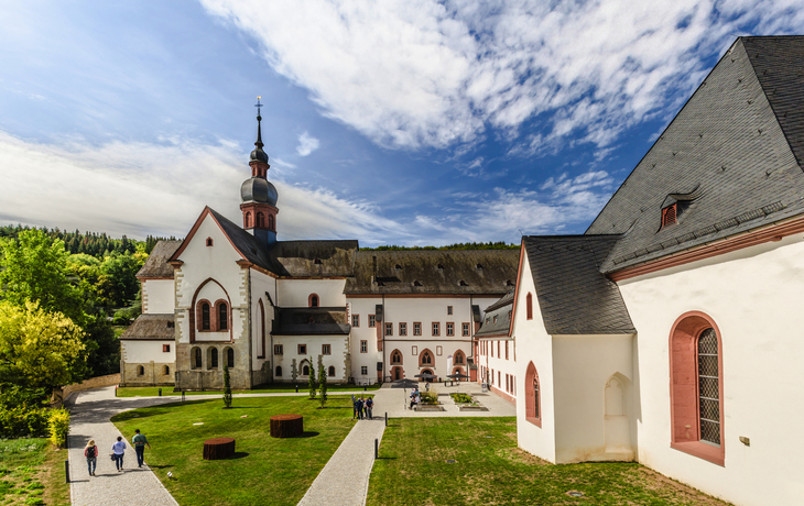 Ehemalige Abtei Eberbach im Rheingau mit Menschen im Innenhof bei sonnigem Wetter.