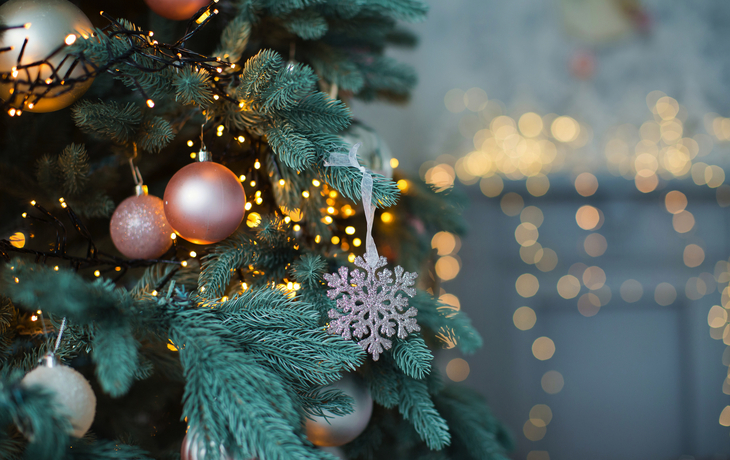 Weihnachtsbaum mit rosa und goldenen Kugeln und Lichterkette.