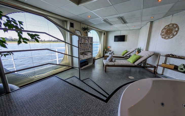 Wellnessbereich mit Liegen und Blick aufs Wasser.
