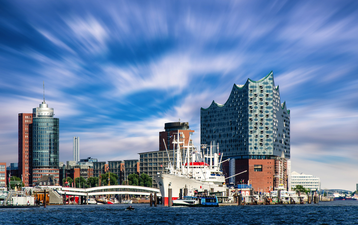 Elbphilharmonie und Schiffe im Hamburger Hafen unter bewölktem Himmel.