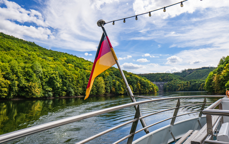 Schiff mit deutscher Flagge auf dem Rursee im Nationalpark Eifel