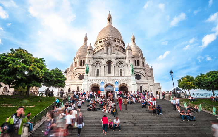 Sacré-Cœur-Basilika auf dem Hügel Montmartre in Paris, umgeben von Menschen.