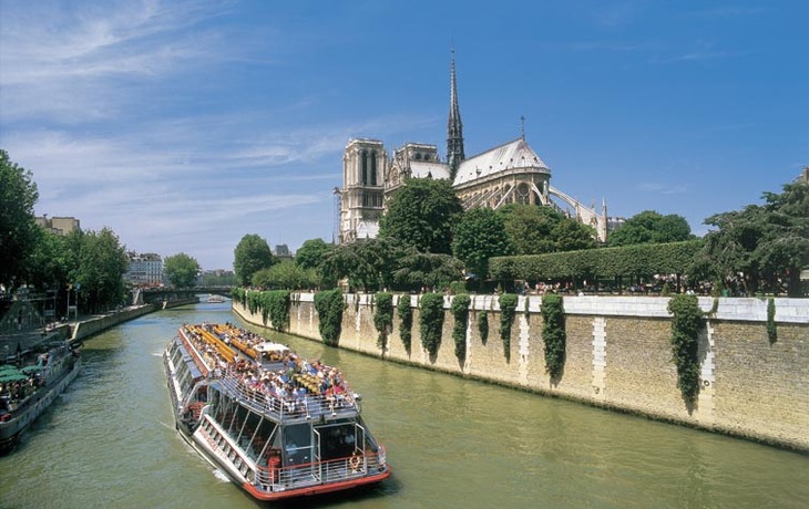 Touristenboot auf der Seine vor der Notre Dame bei sonnigem Wetter