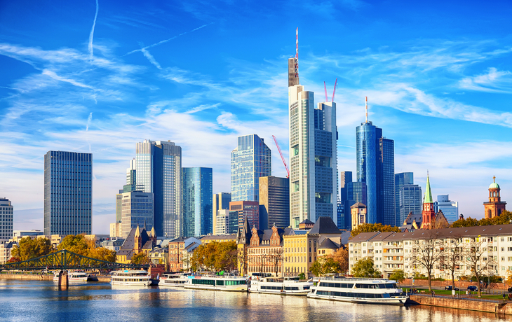 Frankfurts Skyline mit Main und modernen Hochhäusern bei klarem Himmel.