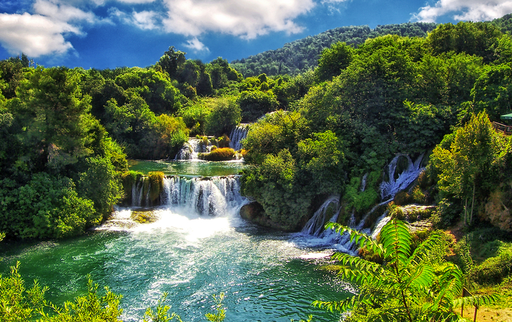 Wasserfälle im grünen Krka-Nationalpark in Kroatien, umgeben von üppiger Vegetation.