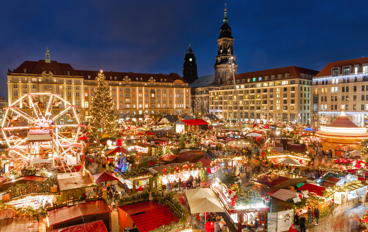 Weihnachtsmarkt bei Nacht mit bunten Ständen und Lichtern in einer Stadt.