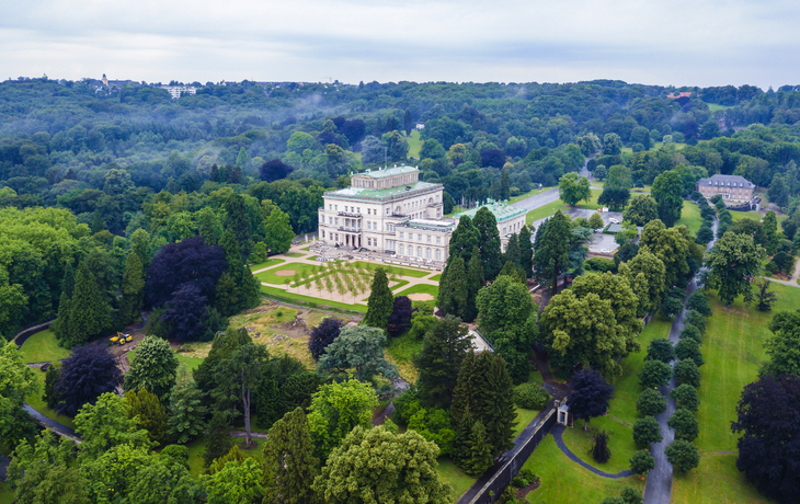 Luftaufnahme eines großen historischen Gebäudes inmitten eines weitläufigen Parks.
