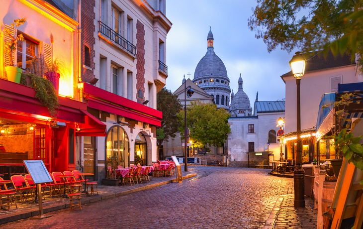Straßenszene in Montmartre, Paris, mit Blick auf Sacré-Cœur bei Abenddämmerung.