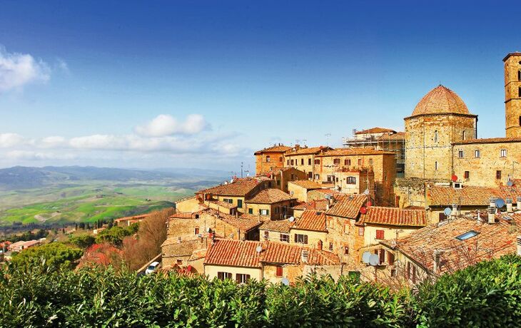 Panoramablick auf Volterra mit historischen Gebäuden und Hügeln im Hintergrund.