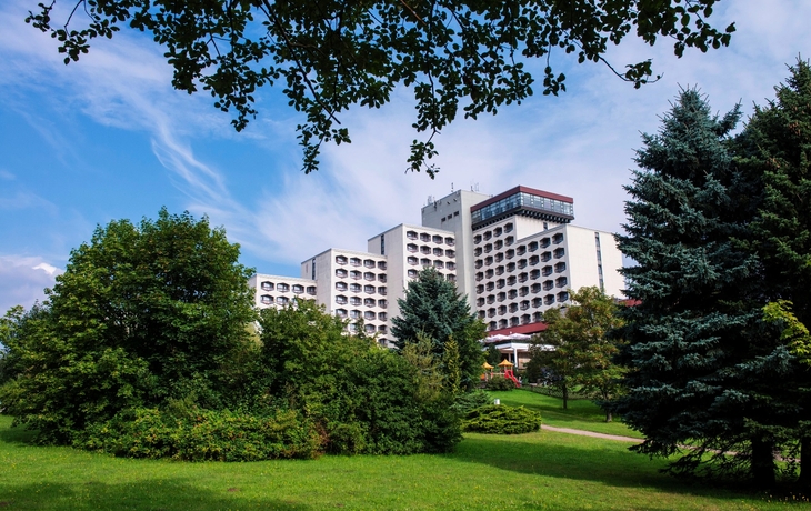 Außenansicht des AHORN Berghotel Friedrichroda im Sommer, umgeben von Bäumen.
