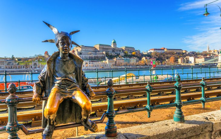Bronzestatue eines Mädchens am Flussufer, Budapest im Hintergrund.