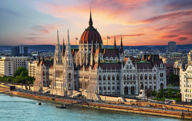 Ungarisches Parlamentsgebäude bei Sonnenuntergang am Donauufer in Budapest.