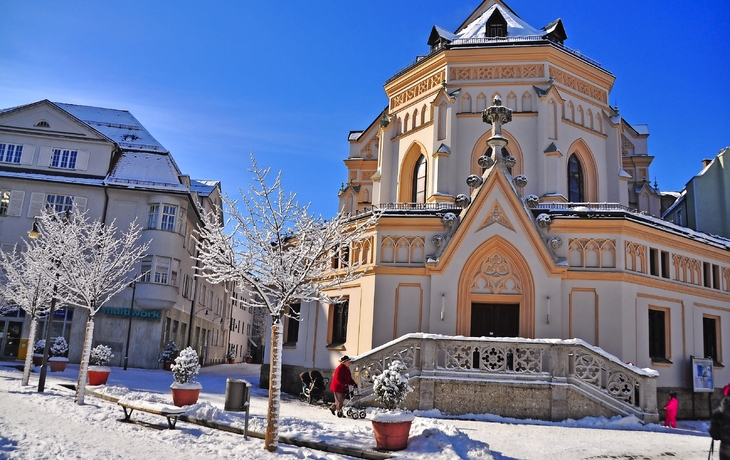 Wintertag in Rosenheim mit einer verschneiten Kirche und blauem Himmel