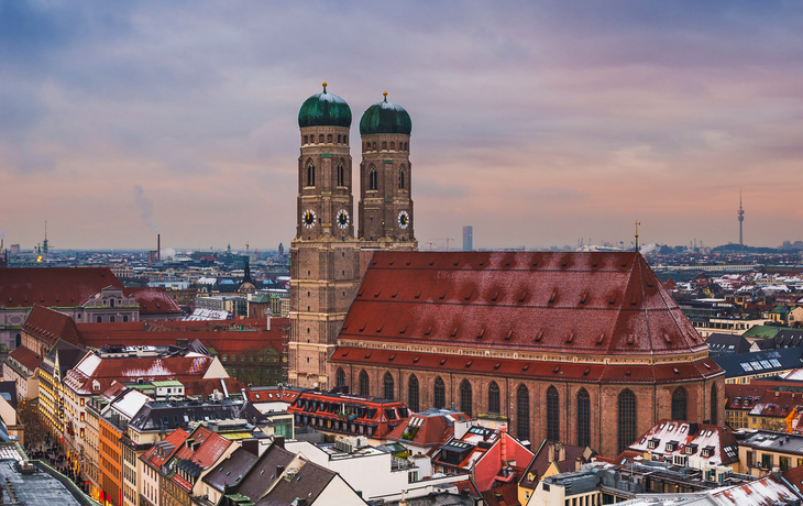 Panorama von München im Winter mit der schneebedeckten Skyline und der Frauenkirche im Vordergrund.
