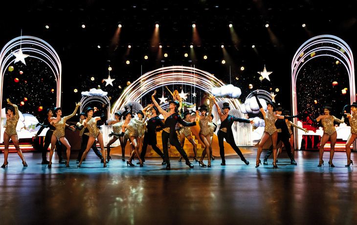 Bunte, kostümierte Tänzer bei der BLINDED by DELIGHT Show im Friedrichstadt-Palast Berlin