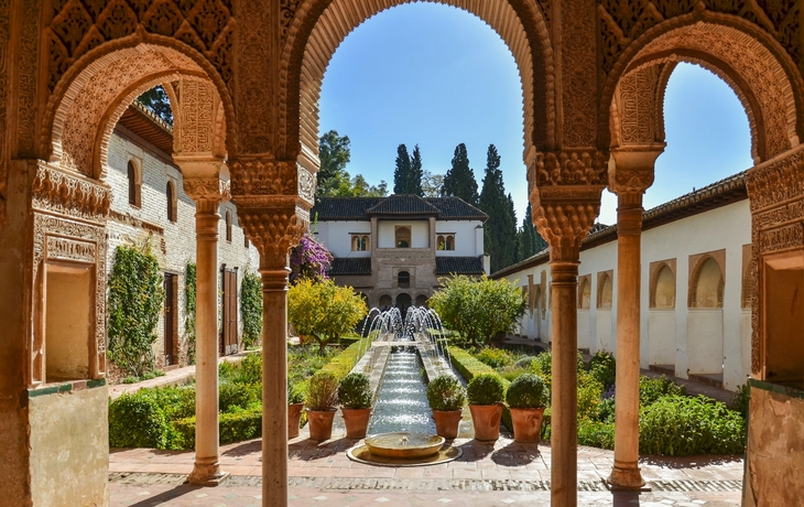 Mittelalterlicher Hof mit Arkaden und Springbrunnen im Garten.