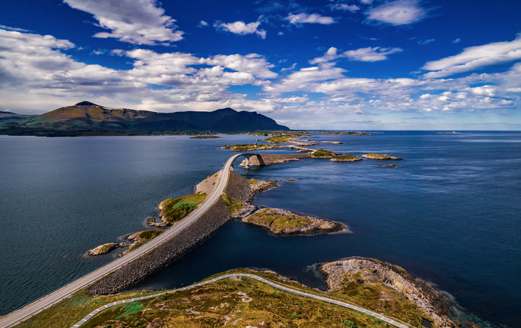 Brücke über das Meer mit Bergen und blauem Himmel im Hintergrund