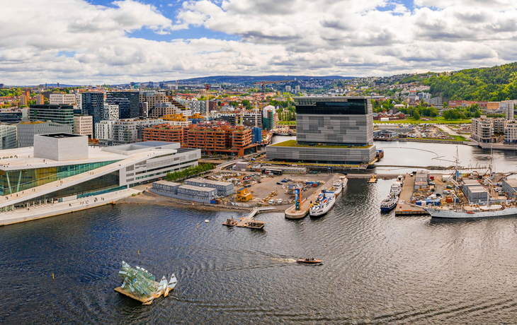 Panorama von Oslo mit Opernhaus und Hafen bei Wolkenhimmel.
