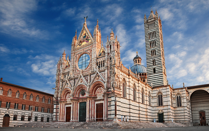 Kathedrale von Siena mit markantem Glockenturm vor blauem Himmel.