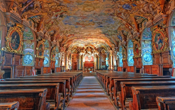 Barocker Kircheninnenraum mit verzierten Wänden und Deckenfresken.