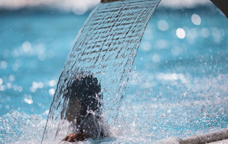 Wasserfall im Spa-Bereich eines Schwimmbads mit sprudelndem Wasser und entspannender Atmosphäre.