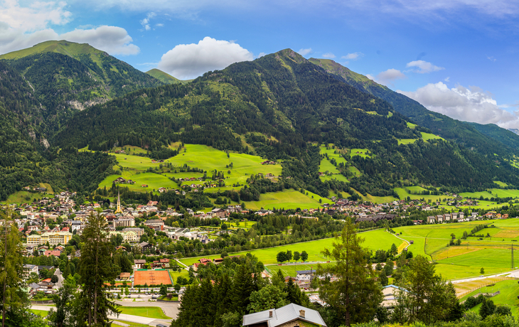 Panorama einer Alpenlandschaft mit grünen Tälern und teilweise wolkenverhangenen Bergen.